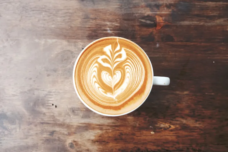 A cappuccino with latte art on a wooden table